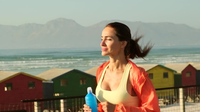 The woman with runner on the street . Athlete running on the road trail in sunset training for marathon and fitness. a sports girl runs along the beach against the background of colorful houses