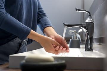 Woman washing hands in bathroom, closeup view