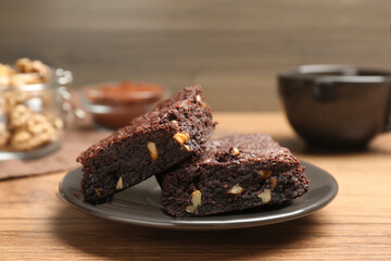 Delicious chocolate brownies with nuts on wooden table, closeup