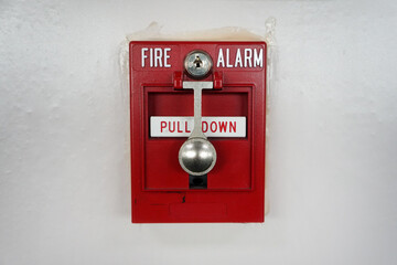 red fire safety alarm button on cement white wall.