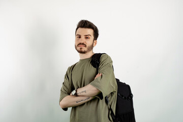 Portrait of cheerful man wearing khaki t-shirt posing isolated over white background confident posing carrying backpack with crossed arms.