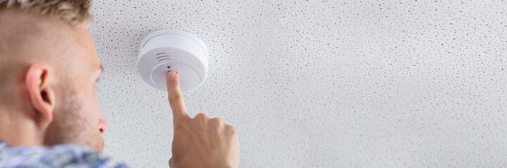 Person's Hand Installing Smoke Detector On Ceiling