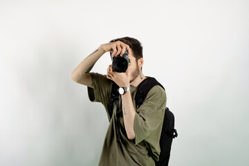 Caucasian man wearing khaki tee posing isolated over white background taking images with dslr camera. Photographer covering his face with the camera.