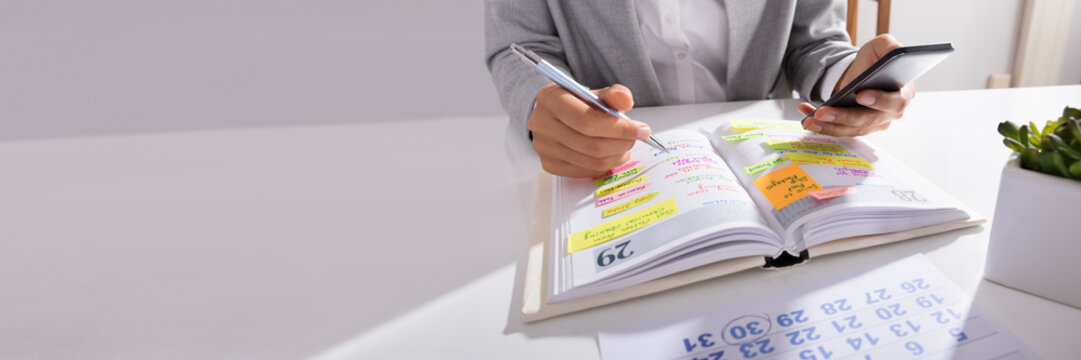 Person Hands With Mobile Phone And List Of Work