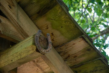 An old worn-out and rusty metal horseshoe nailed to the light grey wooden door of a village house. Horseshoe is a sign of fortune and luck.