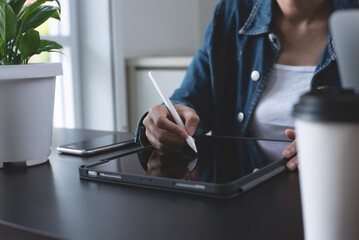 Close up of business woman in casual wear using stylus pen touching on digital tablet screen on...