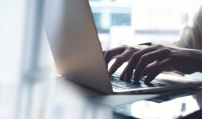 Business man working on laptop computer, typing on laptop keyboard on office table, surfing the...