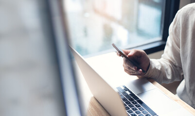Business man using mobile phone and working on laptop computer at office