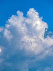 Naklejka na ściany i meble Cumulonimbus cloud under blue sky. Close-up. Vertical