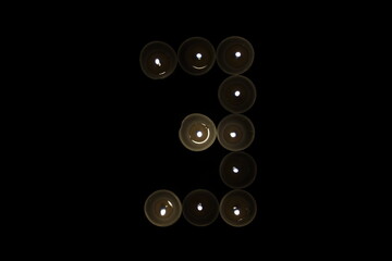 numbers from 1 to 9 made of burning candles isolated on black background