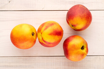 Several ripe juicy nectarines on a wooden table, close-up, top view.