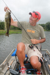 An angler with a largemouth bass caught from small boat 