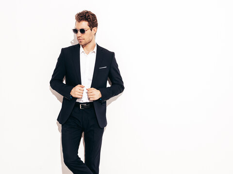 Portrait of handsome confident stylish hipster lambersexual model. Sexy modern man dressed in black elegant suit. Fashion male posing in studio in sunglasses. Isolated