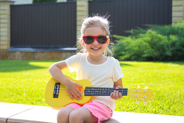 Beautiful girl with guitar positive child summer house lawn