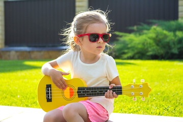 Beautiful girl with guitar positive child summer house lawn