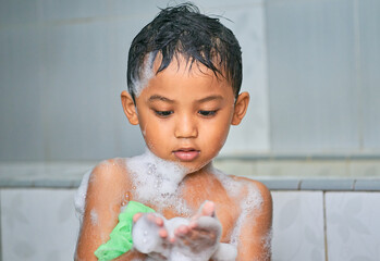 Cute asian boy taking a shower with soap foam on his body