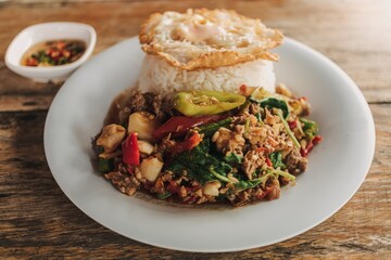 Thai Rice topped with stir-fried minced beef basil and fried egg on white dish.
