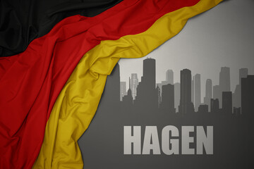 abstract silhouette of the city with text Hagen near waving national flag of germany on a gray background.