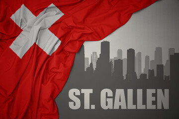 abstract silhouette of the city with text St. Gallen near waving national flag of switzerland on a gray background.