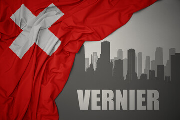 abstract silhouette of the city with text Vernier near waving national flag of switzerland on a gray background.