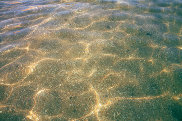 Transparent sea water, sun rays, sand at the bottom. Summer vacation. Rest, relaxation
