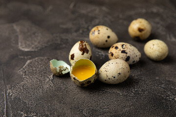 Obraz premium Quail eggs on a black texture background. Whole and broken quail eggs. Natural products. Place for text. Fresh quail eggs.