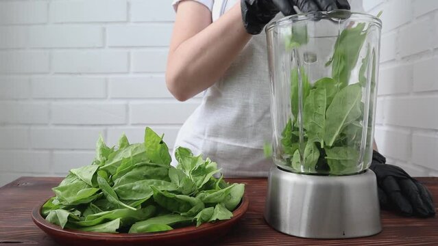Women's hands shift fresh spinach into a blender for making smoothies. The concept of healthy eating. High quality Full HD footage.