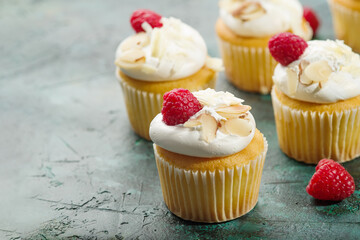 Sweet berry muffins with cream, raspberries and almonds on a dark green background. Banquet, picnic, birthday. Book of recipes. Restaurant and home cooking. Advertising, banner.