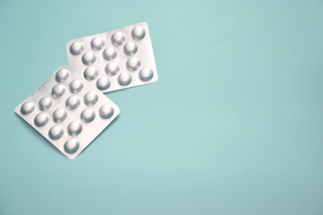 Tablets in a silver blister on a blue background. Free space for text. Pharmaceuticals, medicines, vitamins, bioadditives.
