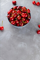 Sweet cherries in bowl. Ripe cherry on a gray background. Freshly picked cherry berries on concrete. Copy space