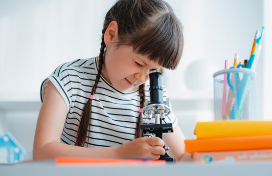School girl with microscope for school education at home