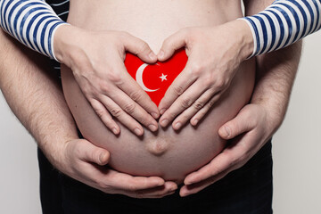 Turkish family concept. Man embracing pregnant woman belly and heart with flag of Turkey colors...