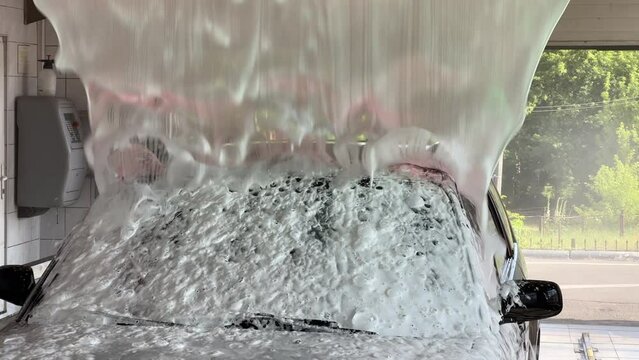 Automatic car wash. Active foam is supplied to the car from automatic sprayers.