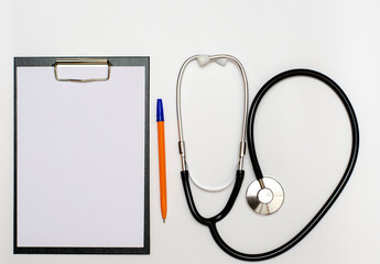 In the doctor's office, on the table is a stethoscope, a medical device for listening to the heartbeat, a tablet with a sheet of paper for recording, copy space