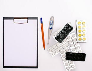 A universal tablet, a notebook for writing a prescription by a doctor, a medical thermometer and medicines on the table. copy space.