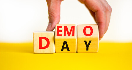 Demo day symbol. Concept words Demo day on wooden cubes. Businessman hand. Beautiful yellow table...
