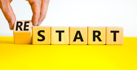 Start or restart symbol. Businessman turns wooden cubes and changes the concept word Start to Restart. Beautiful yellow table white background. Business start or restart concept. Copy space. - obrazy, fototapety, plakaty