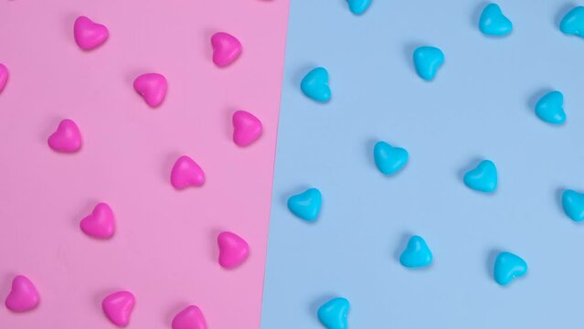 Rotating pink and blue background with heart shaped candies, concept of a gende party, trendy sweet background