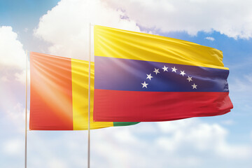 Sunny blue sky and flags of venezuela and guinea