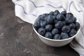 Blueberries in a ceramic bowl on a black textured background. Ripe and fresh blueberries. Vitamins. Healthy food. Juicy berry.Copy space.Place for text