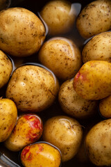 Overhead view of fresh organic potatoes in bowl with water