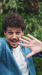 Close-up, young bearded man doing stream, video call on green leaves background