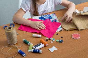 Close-up of a little girl sewing things by herself. Creates a product with his own hands. The child...