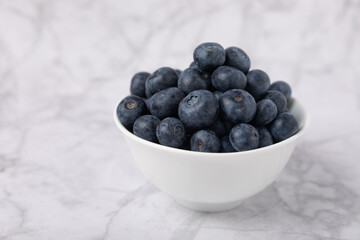 Blueberry. Ripe and fresh blueberries in a plate on a marble background. Vitamins. Healthy food. Juicy berry. Copy space. Place for text