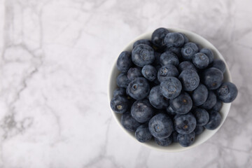Blueberry. Ripe and fresh blueberries in a plate on a marble background. Vitamins. Healthy food. Juicy berry. Copy space. Place for text