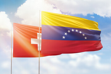 Sunny blue sky and flags of venezuela and switzerland