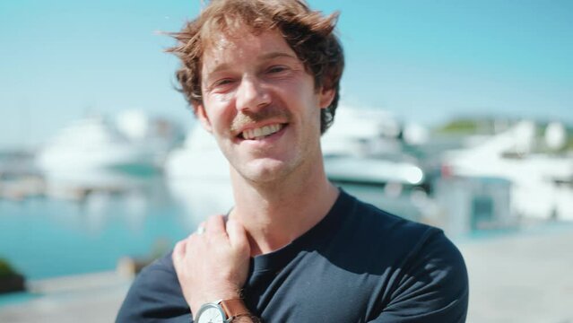 Smiling blond man looking at the camera on the embankment at summer