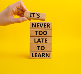 It's Never to Late to Learn symbol. Wooden blocks with words It's Never to Late to Learn. Beautiful yellow background. Businessman hand. Business and It's Never to Late to Learn. Copy space.