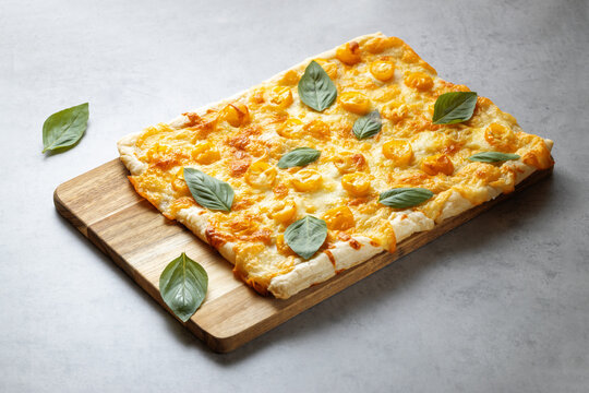 homemade pizza with basil, tomatoes and mozzarella cheese, on a wooden board