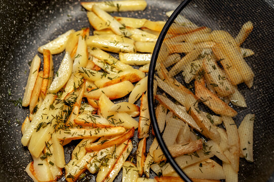 fried ruddy potatoes in a frying pan , under a grid lid